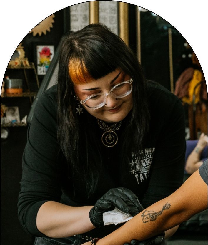 Rachel, a resident tattoo artist, wiping the arm of a client who just got a tattoo inside the Black Magic Tattoo studio.